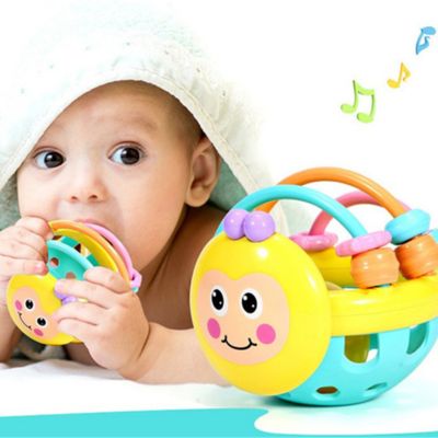 Bébé mordillant une balle sensorielle de préhension avec éléments de dentition, hochet d’éveil favorisant la motricité fine et l’exploration sensorielle