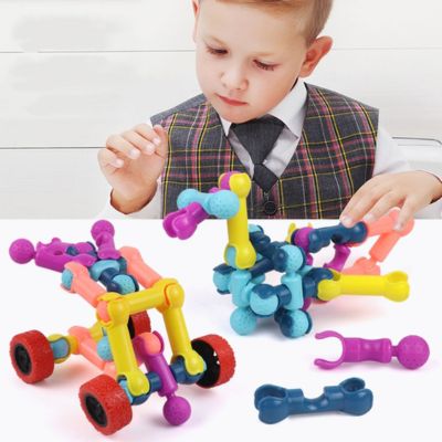 Enfant assemblant des blocs de construction articulés STEM pour créer des véhicules et structures colorées, jeu éducatif développant la motricité fine et l’imagination