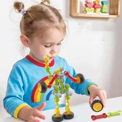 Bébé jouant avec des blocs de construction articulés STEM pour créer des formes et véhicules colorés, jeu d’éveil favorisant la motricité fine et la créativité