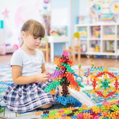 Enfant construisant une grande structure 3D avec des blocs flocon de neige STEM, jeu créatif favorisant l’imagination, la concentration et la motricité fine