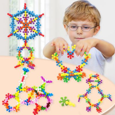 Enfant créant différentes formes colorées avec des blocs flocon de neige STEM, jeu éducatif développant la créativité, la logique et la concentration