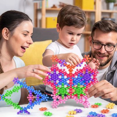 Parents et enfant construisant ensemble avec des blocs flocon de neige STEM, jeu de construction créatif favorisant le partage, la créativité et l’apprentissage
