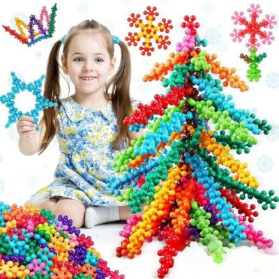 Enfant construisant un grand sapin coloré avec des blocs flocon de neige STEM, jeu de construction créatif stimulant l’imagination et la coordination