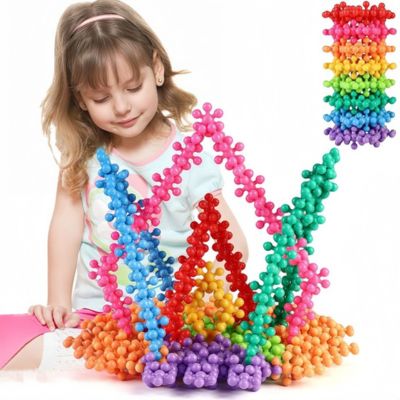 Enfant construisant une grande structure colorée avec des blocs flocon de neige STEM, jeu de construction créatif favorisant l’imagination et la motricité fine