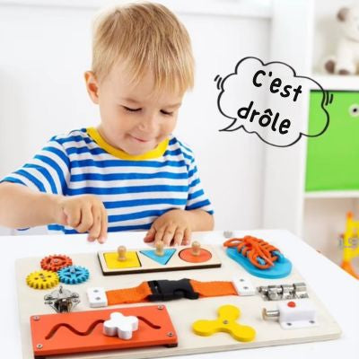 Enfant jouant avec une planche d’activité Montessori en bois type busy board, jouet éducatif stimulant la motricité fine, la logique et l’autonomie
